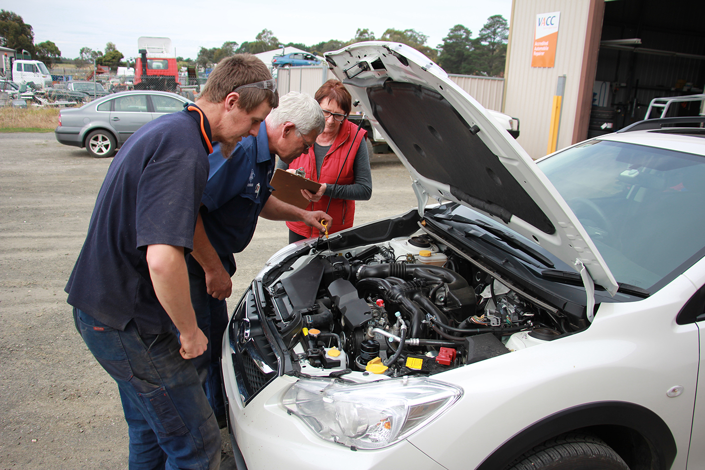 Chris and Cheryl Johnston checking over a car with a mechanic outside the workshop at Beaufort