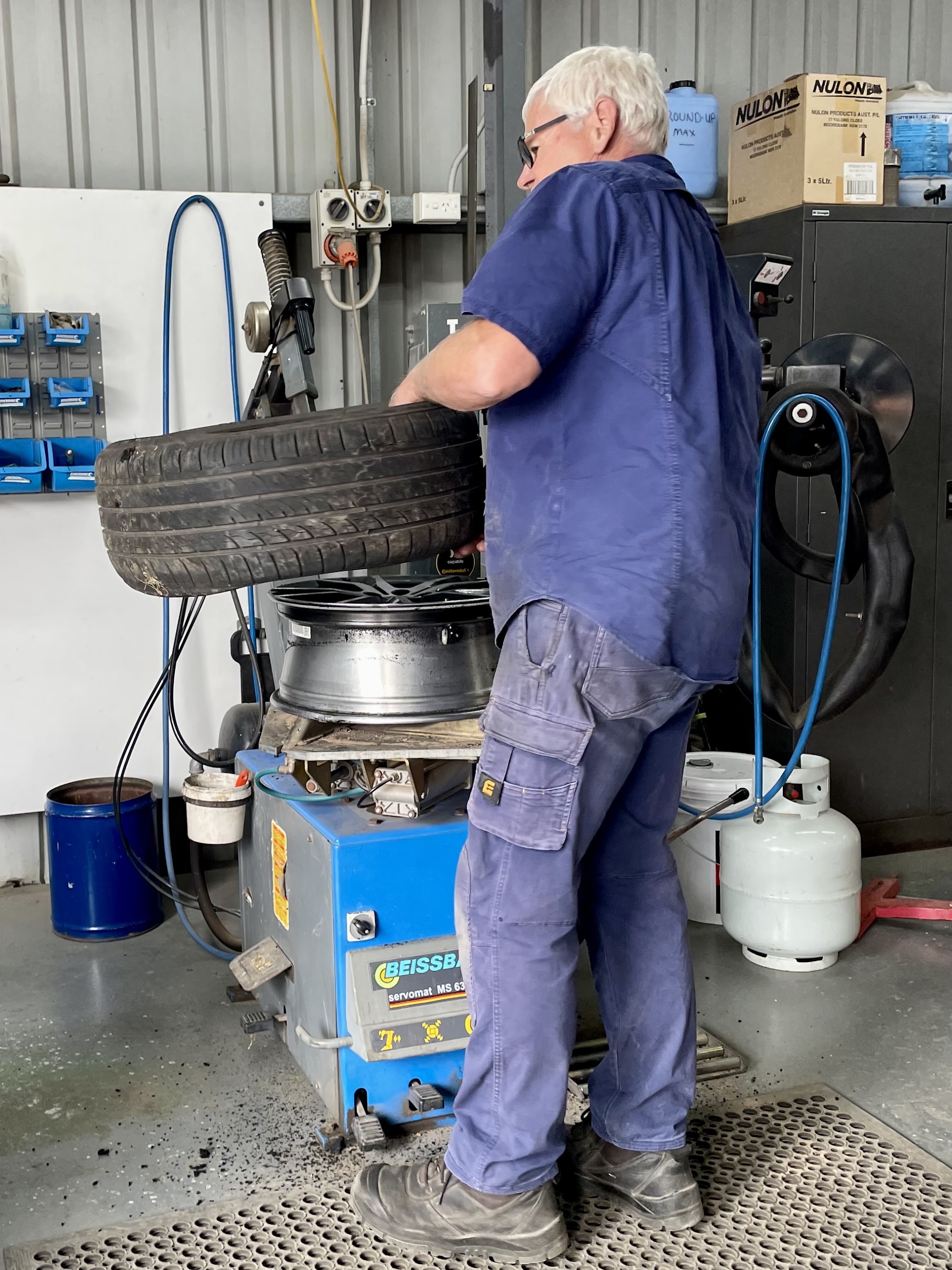 Chris Johnston lifting a tyre onto an alloy rim on the tyre machine in the Beaufort workshop